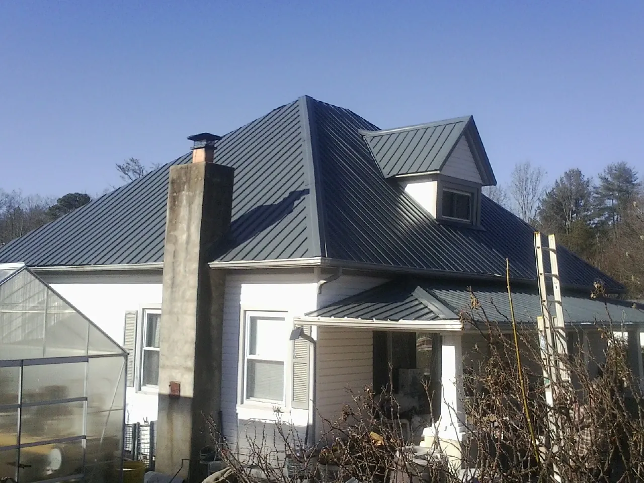 Dark blue standing seam metal roof on a white farmhouse with dormer — Slate & Tile Roof Repair by Roofing Brothers in Airway Heights