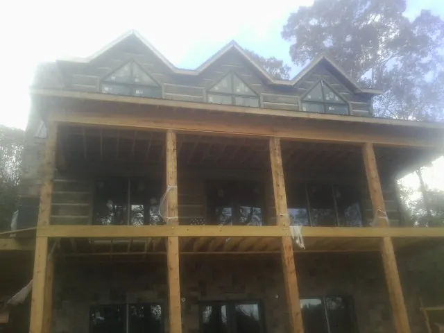 Dormers and porch framing on a large log home under construction — Roof Coating work by our crew in Airway Heights