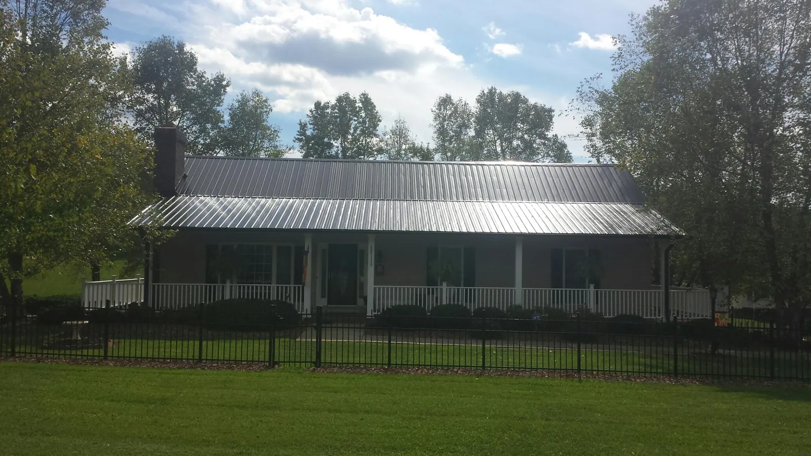Gray metal roof on a brick ranch with a full width front porch — Gutter Guard Installation work by our crew in Airway Heights