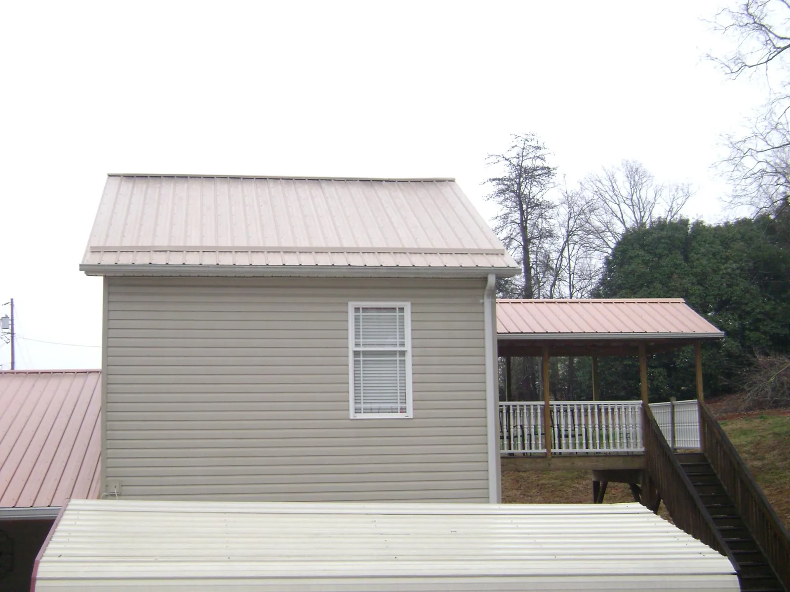 Tan metal roofs on a two story addition and attached porch, from a Roof Replacement job in Airway Heights