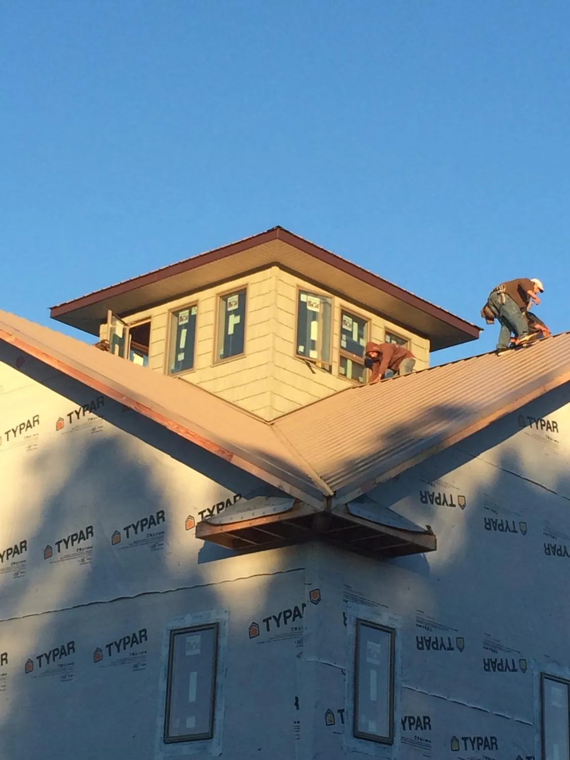 Roofers working around a rooftop cupola on a new metal roof at sunset — Roof Waterproofing in Airway Heights by Roofing Brothers